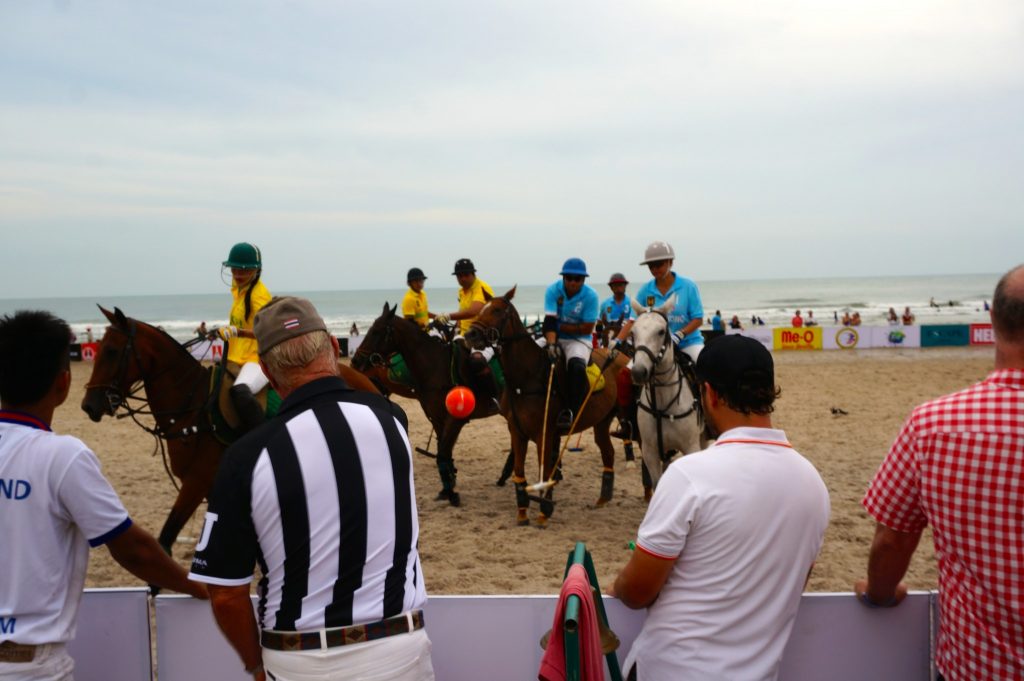Referee throws ball in to beach polo match