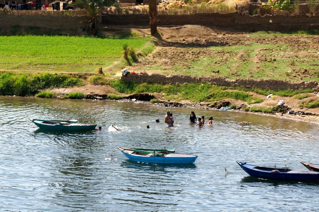 small row boats and more children swimming in the Nile