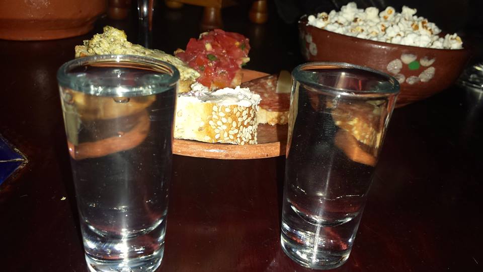 Two shot glass of Pox (grain alcohol made from sugarcane) with a plate of botanas