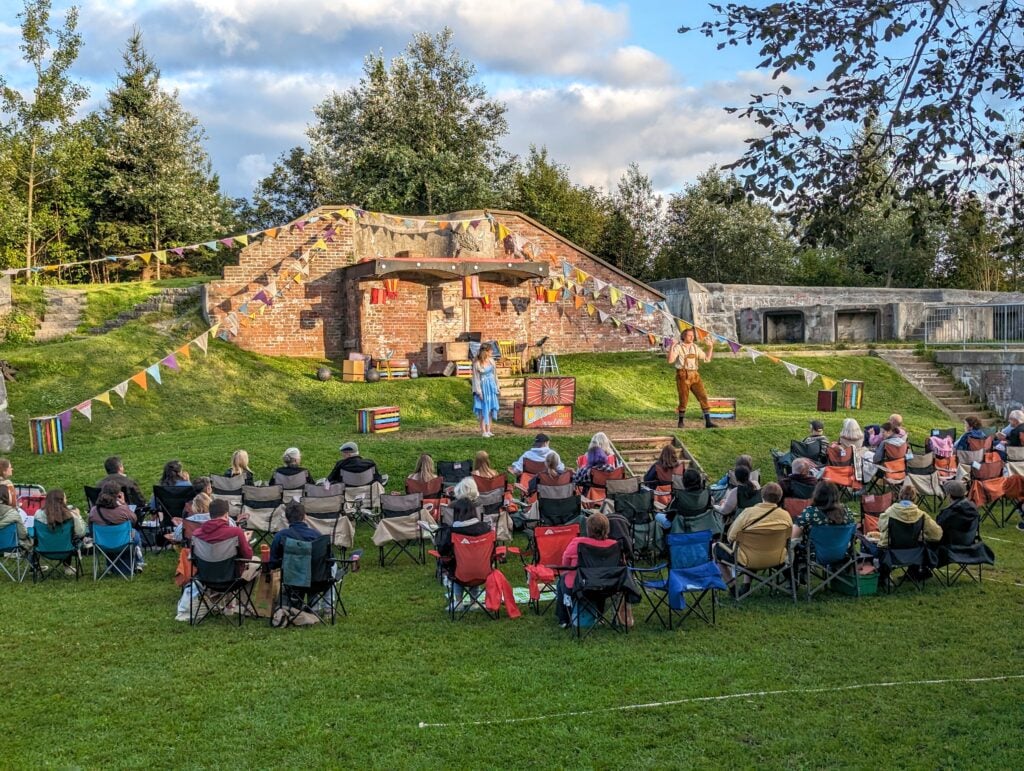 Outdoor theatre-goers in chairs getting ready to watch the outdoor play in the park